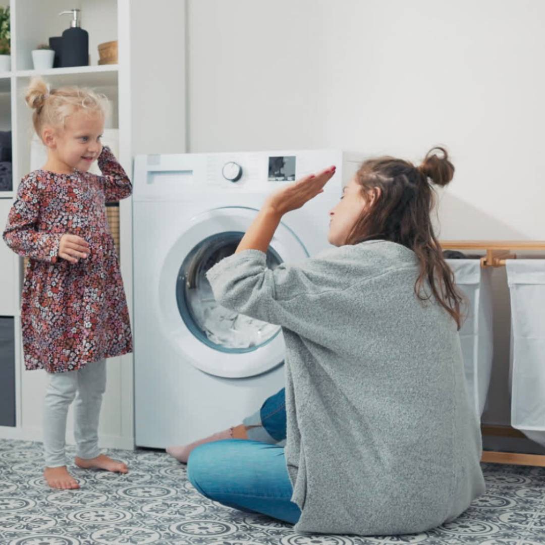 Moeder en dochter bij wasmachine met EcoWashly wasstrips – huidveilig, plasticvrij en getest volgens Duitse en Europese milieunormen, aanbevolen door experts.
